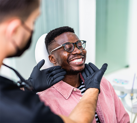 Male patient with glasses and pink shirt having teeth checked