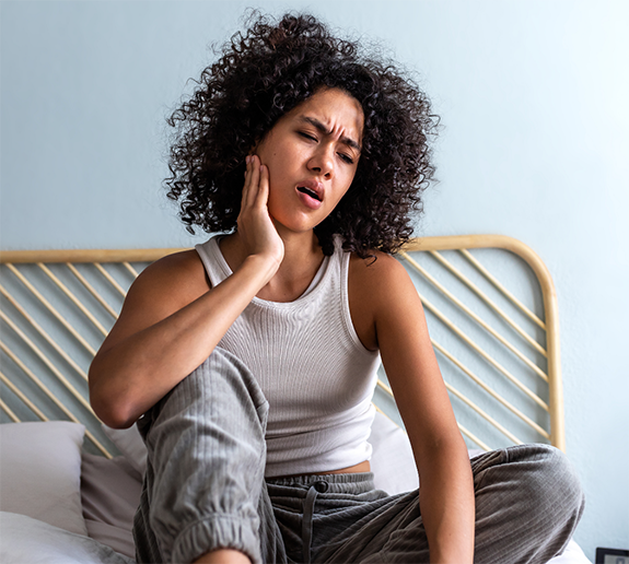 Woman sitting on bed with jaw pain