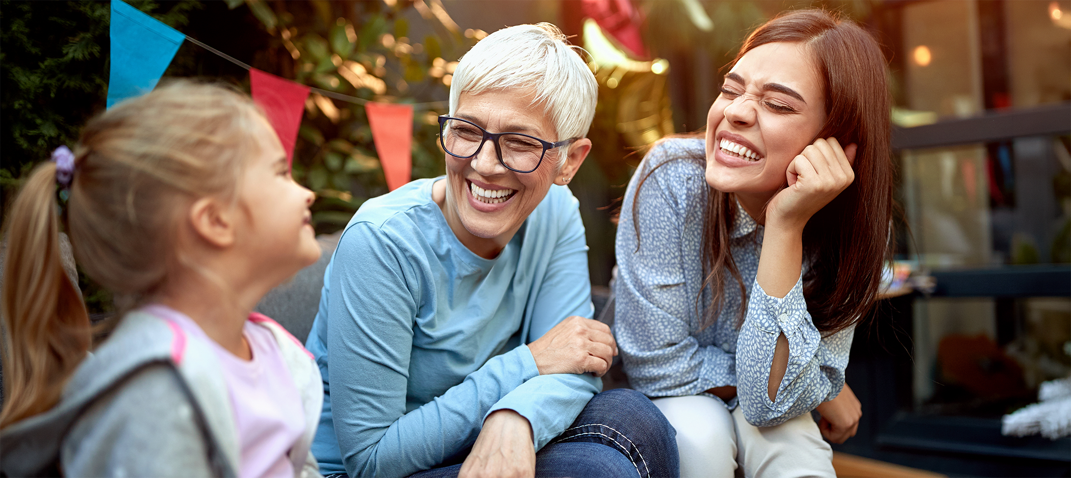 Little girl and two women sitting and smiling at each other