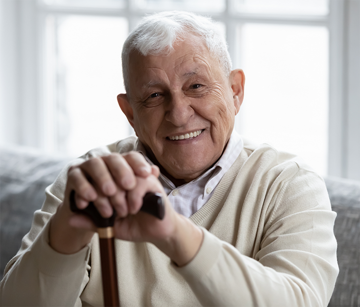 Senior man with cane sitting on couch
