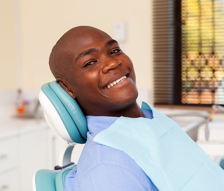 Man leaning back in dental chair and smiling