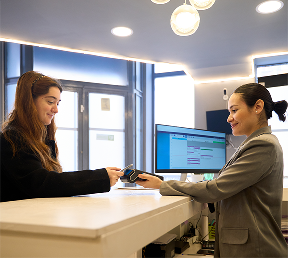 Front desk team member holding out credit card reader for patient