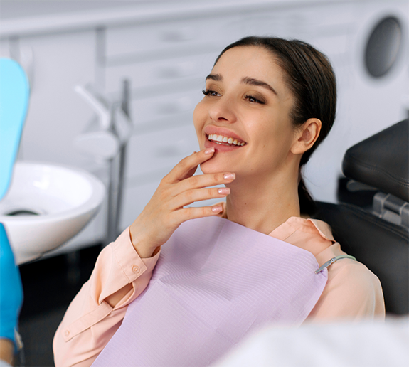 Female patient in dental chair touching her teeth