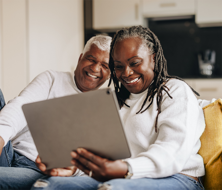 Man and woman sitting on couch and looking at a tablet