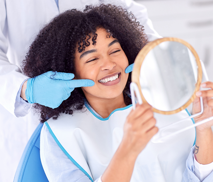 Female patient holding a mirror to check teeth